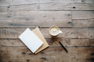 Notizbücher und ein Barista-Kaffee auf einem rustikalen Holztisch – denn das Erstellen von Lückentexten ist mit dem Worksheet Crafter ganz einfach.